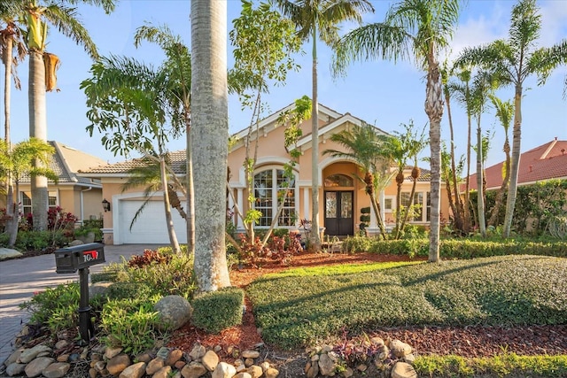 mediterranean / spanish-style house with driveway, a front lawn, an attached garage, and stucco siding