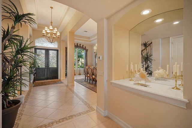 foyer entrance featuring arched walkways, light tile patterned floors, recessed lighting, a raised ceiling, and baseboards