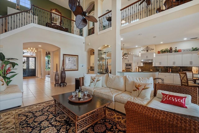 living room featuring ceiling fan with notable chandelier, arched walkways, and light tile patterned floors