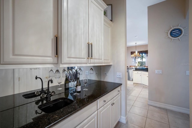 kitchen with dark stone counters, white cabinetry, and a sink