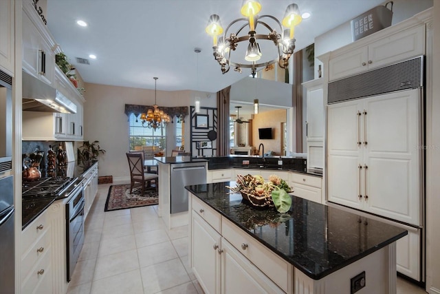 kitchen with stainless steel appliances, hanging light fixtures, white cabinets, a kitchen island, and a chandelier