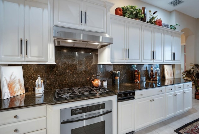 kitchen featuring white cabinets, visible vents, oven, and under cabinet range hood