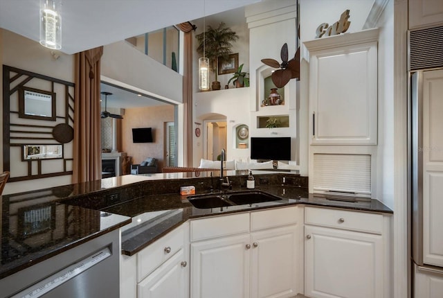 kitchen with arched walkways, open floor plan, white cabinetry, and a sink