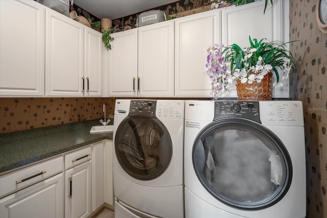 clothes washing area with cabinet space, independent washer and dryer, and wallpapered walls