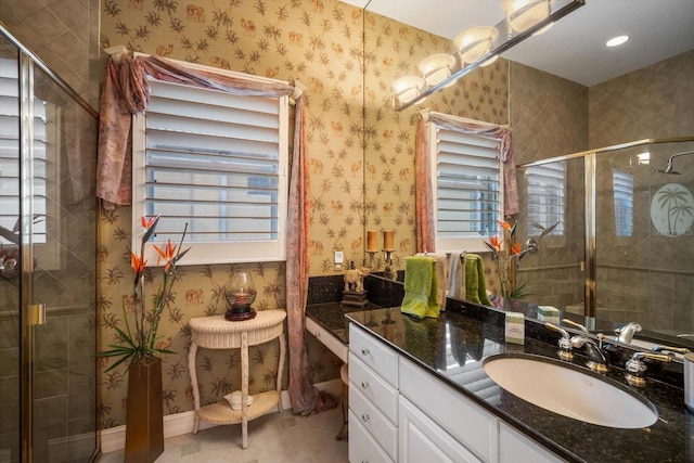 bathroom featuring tile patterned flooring, vanity, baseboards, a shower stall, and wallpapered walls