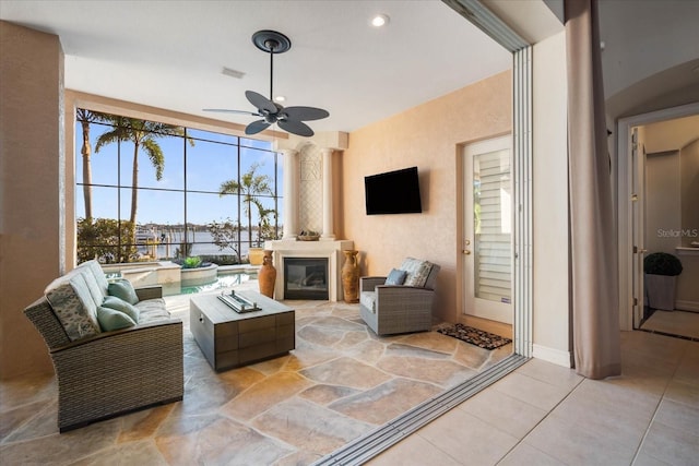 living area featuring a textured wall, a fireplace, visible vents, and a ceiling fan