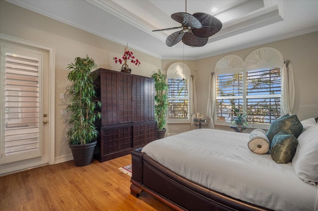 bedroom featuring ornamental molding, a raised ceiling, ceiling fan, and light wood finished floors