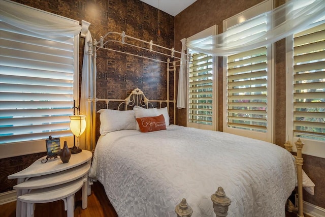 bedroom with wallpapered walls and wood finished floors