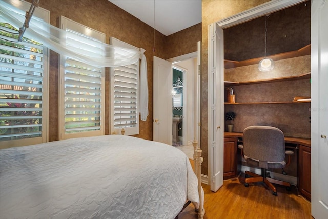 bedroom with built in desk and wood finished floors