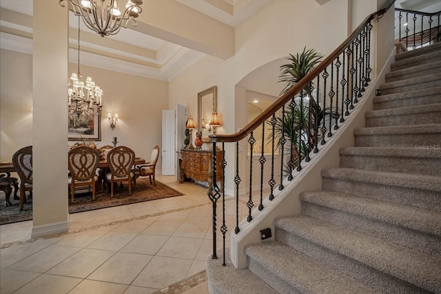 staircase featuring baseboards, a raised ceiling, a towering ceiling, tile patterned floors, and a chandelier