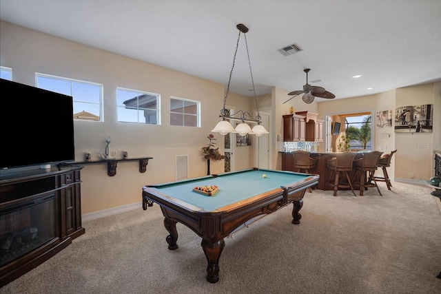 game room featuring indoor wet bar, visible vents, a glass covered fireplace, light carpet, and baseboards