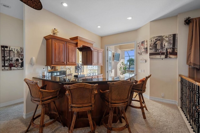 kitchen featuring dark countertops, carpet flooring, a peninsula, and baseboards