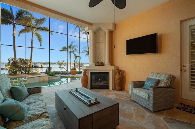 living room with decorative columns, expansive windows, stone tile flooring, and a textured wall