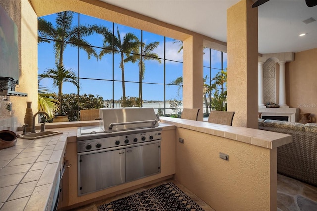 view of patio / terrace featuring ceiling fan, a sink, visible vents, a grill, and exterior kitchen