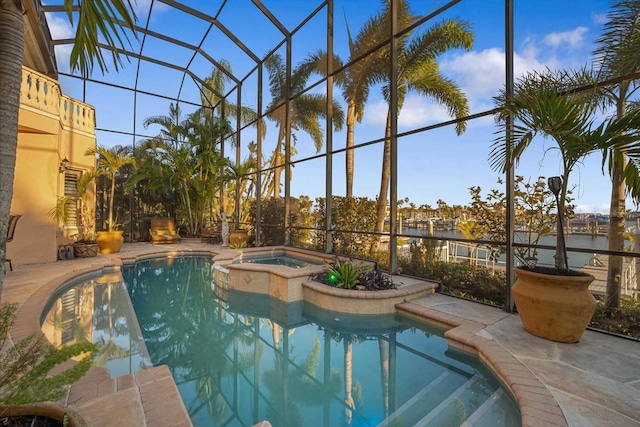 view of pool featuring a patio area, glass enclosure, a water view, and a pool with connected hot tub