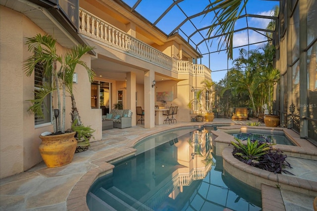 pool featuring a lanai, a patio area, a bar, and an in ground hot tub