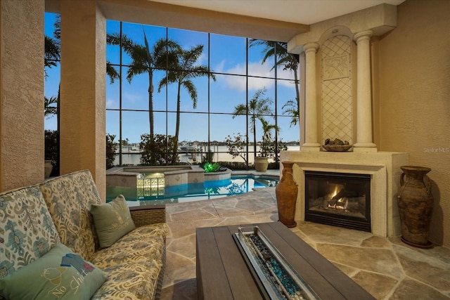 view of swimming pool with a glass covered fireplace, a pool with connected hot tub, and a patio