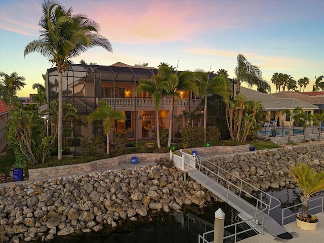 back of house featuring glass enclosure and an outdoor pool