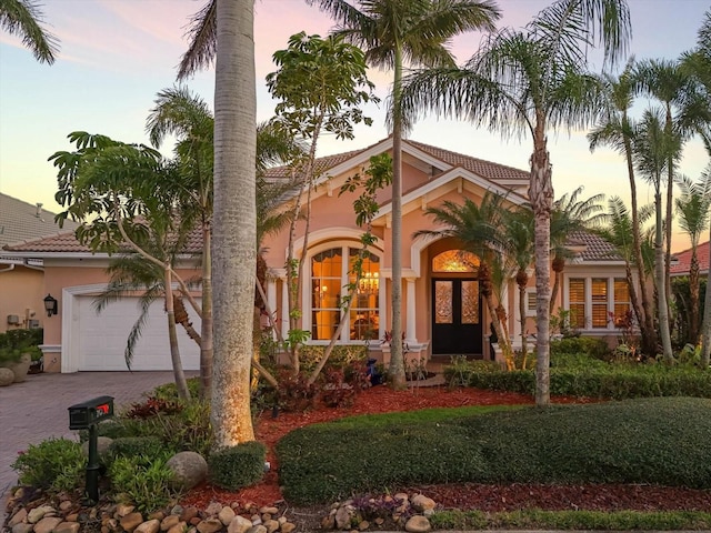 mediterranean / spanish house with a tiled roof, decorative driveway, and stucco siding