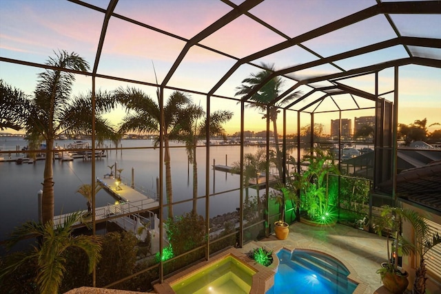 view of pool with a dock, glass enclosure, a water view, and an in ground hot tub