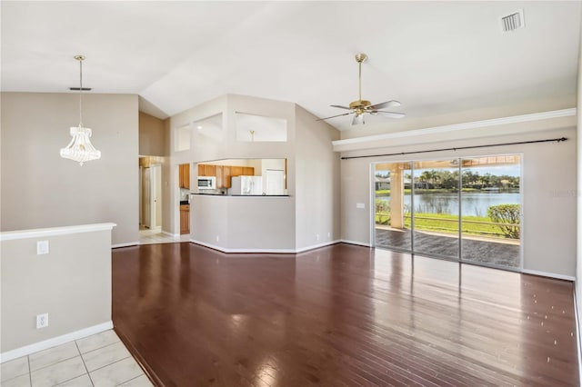 unfurnished living room with light hardwood / wood-style flooring, vaulted ceiling, ceiling fan, and a water view