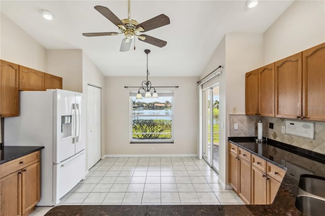 kitchen with lofted ceiling, light tile patterned floors, tasteful backsplash, white fridge with ice dispenser, and decorative light fixtures