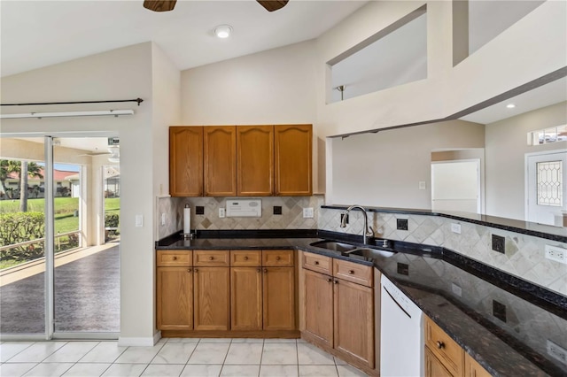 kitchen with light tile patterned floors, white dishwasher, sink, and dark stone countertops