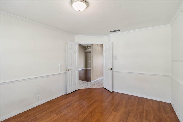 spare room with ornamental molding and light hardwood / wood-style flooring