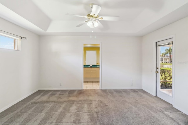 carpeted spare room featuring a raised ceiling, a wealth of natural light, and ceiling fan