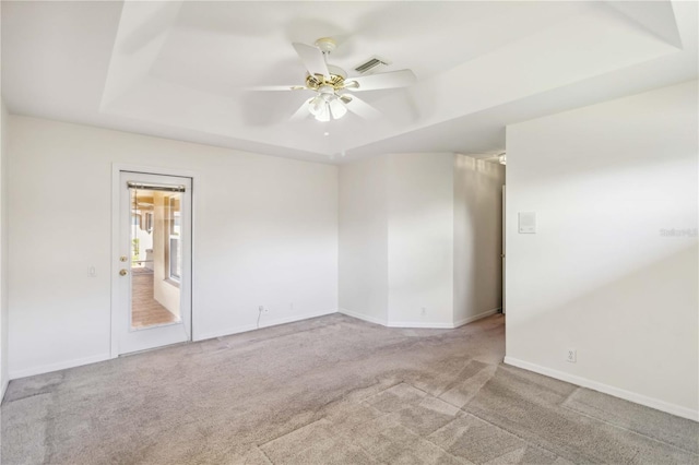 carpeted empty room with a raised ceiling and ceiling fan