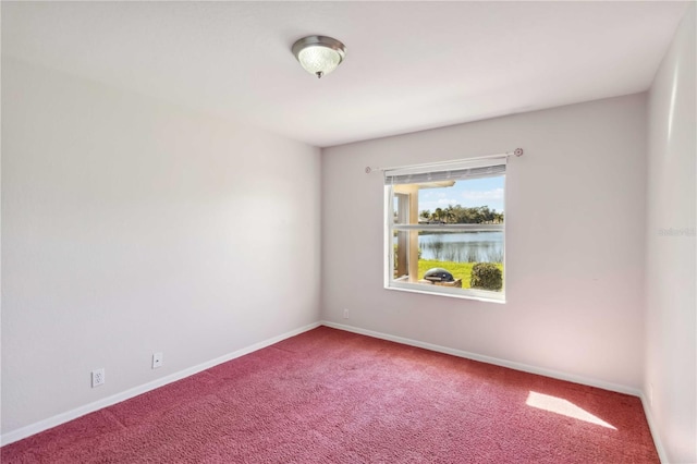 carpeted spare room featuring a water view