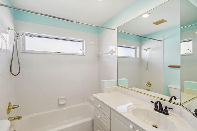 full bathroom featuring tiled shower / bath, vanity, and toilet