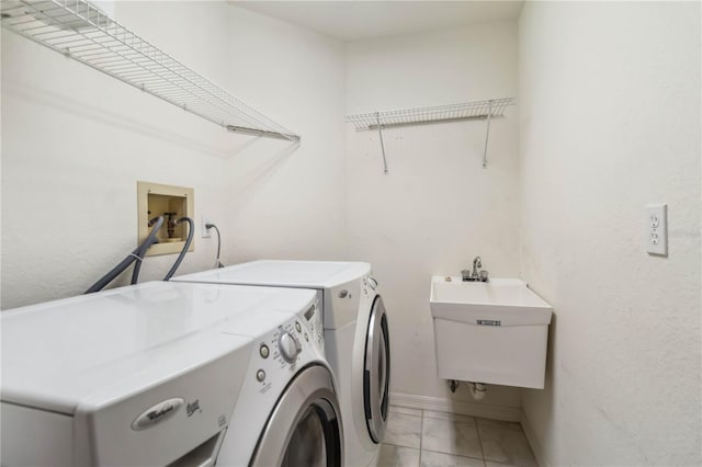 laundry area featuring sink, light tile patterned floors, and washing machine and clothes dryer