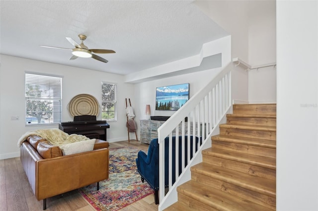 living room with hardwood / wood-style flooring, ceiling fan, and a textured ceiling