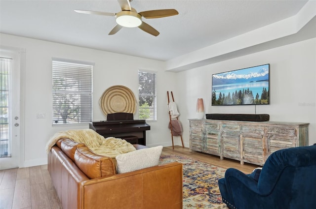 living room with light hardwood / wood-style flooring, ceiling fan, and plenty of natural light