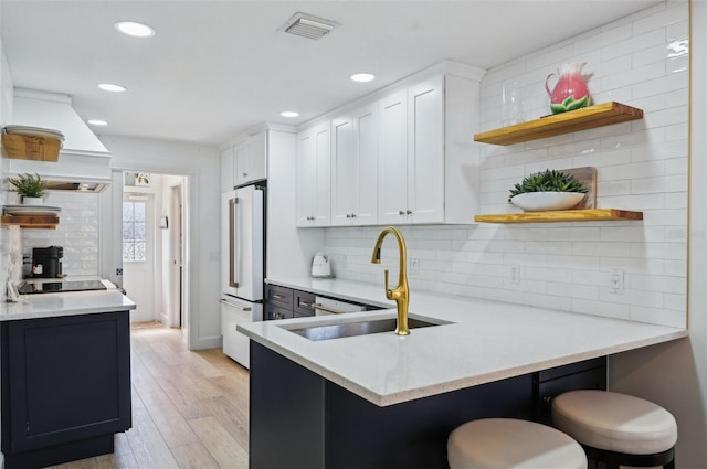 kitchen with white cabinetry, high end refrigerator, a kitchen breakfast bar, and kitchen peninsula