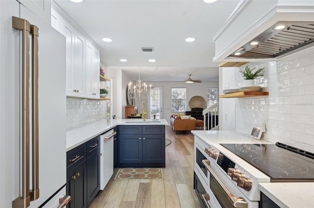 kitchen with sink, white appliances, premium range hood, decorative light fixtures, and kitchen peninsula