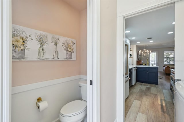 bathroom with hardwood / wood-style flooring, vanity, an inviting chandelier, and toilet