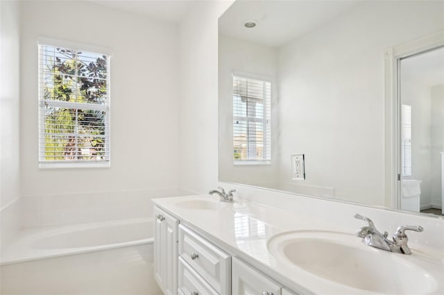 bathroom with vanity, a bathing tub, and a healthy amount of sunlight