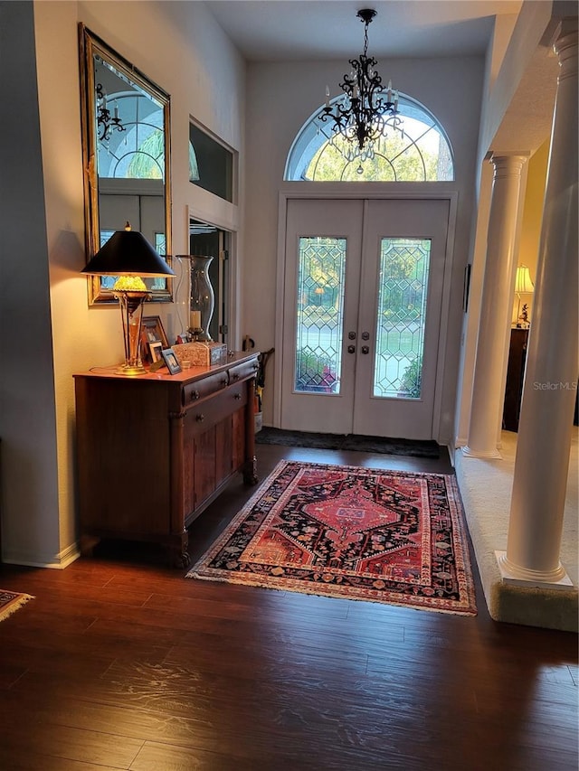 entryway with french doors, dark hardwood / wood-style flooring, a chandelier, and decorative columns