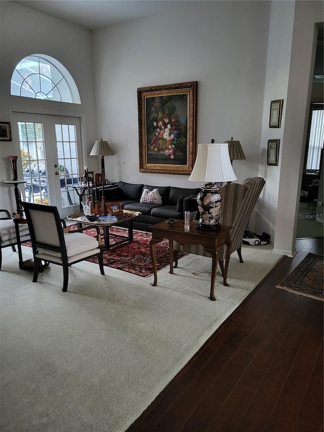 living room with wood-type flooring, a towering ceiling, and french doors