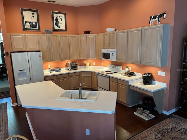 kitchen with dark wood-type flooring, white appliances, and an island with sink