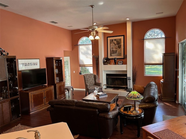 living room featuring plenty of natural light, a tile fireplace, dark hardwood / wood-style floors, and ceiling fan