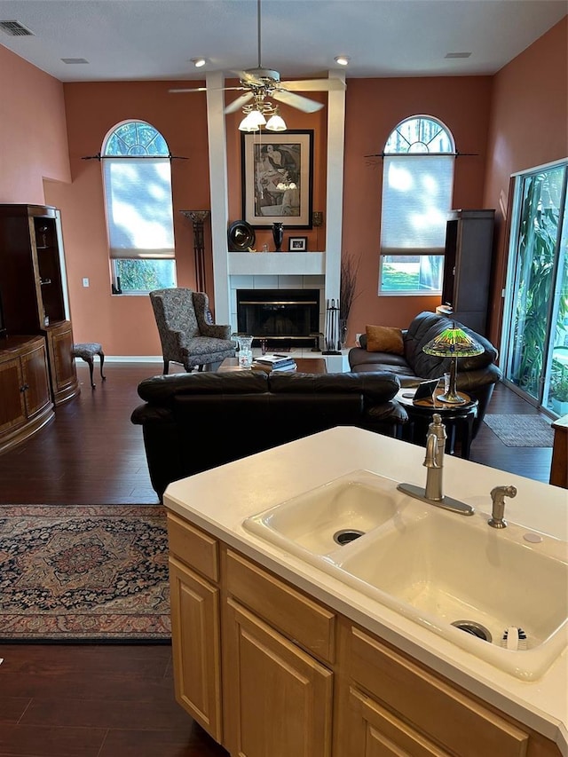 kitchen with dark hardwood / wood-style floors, light brown cabinetry, a fireplace, sink, and ceiling fan