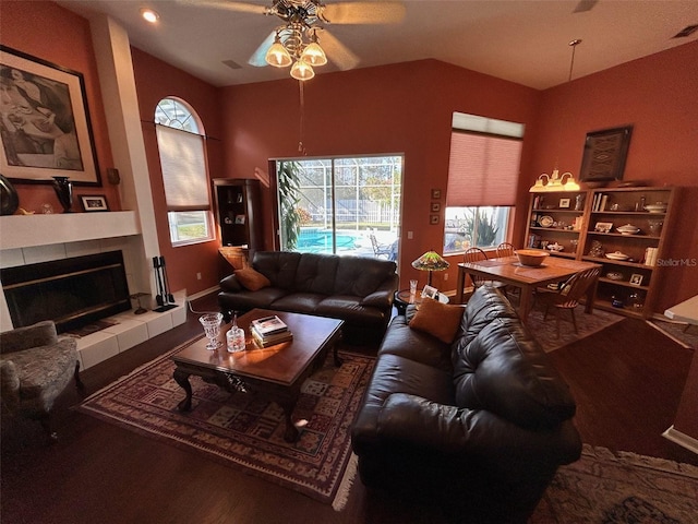 living room with ceiling fan, lofted ceiling, and a tile fireplace