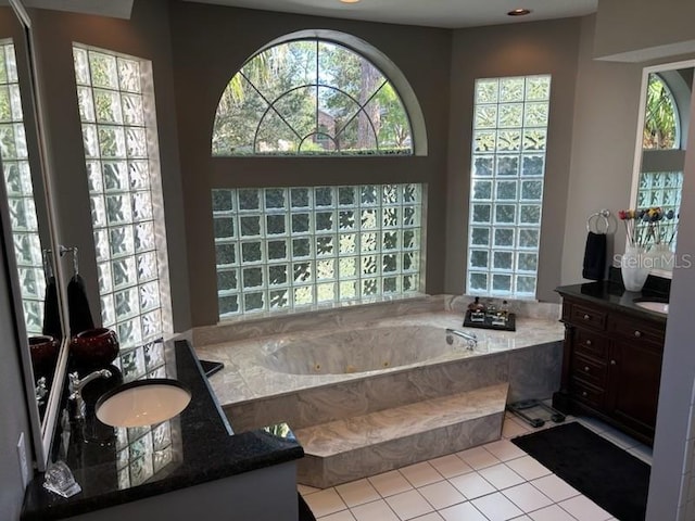 bathroom with vanity, a healthy amount of sunlight, a relaxing tiled tub, and tile patterned floors