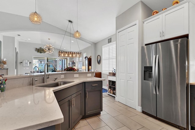 kitchen with vaulted ceiling, plenty of natural light, stainless steel fridge, and a sink