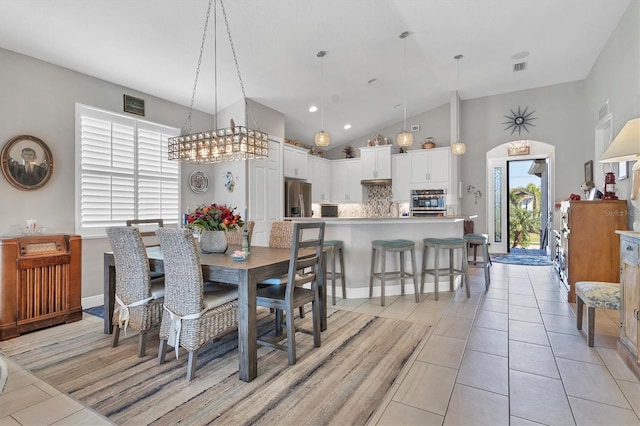 dining room featuring light tile patterned floors, visible vents, and high vaulted ceiling