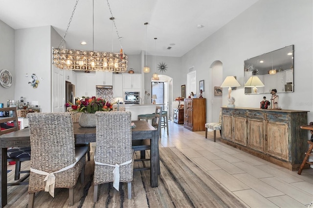 dining room with arched walkways, a high ceiling, and light tile patterned flooring