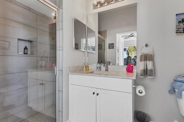 bathroom with vanity, toilet, a ceiling fan, and a stall shower